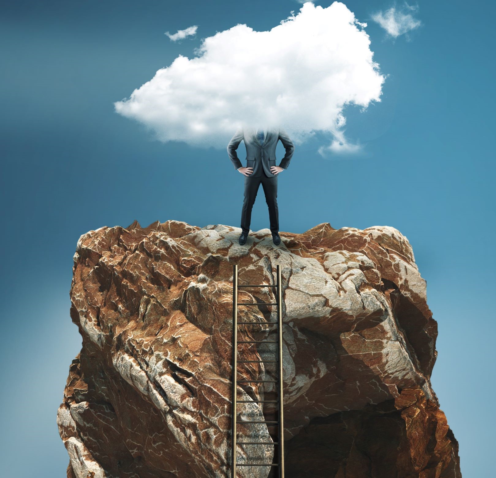 Man at the top of a ladder on a rock with his head in the clouds